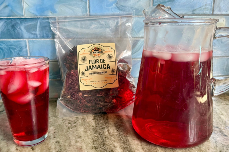 A pitcher and a glass of hibiscus tea sit on a counter.